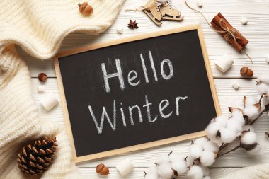 Yazılı tebeşir tahtası Hello Kışları, marşmelovlar, pamuk çiçekler ve beyaz ahşap arka planda süveter