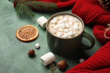 Bir fincan marşmelovlu kakao, süveter ve yeşil grunge arka planda Noel dalları, yakın plan. Merhaba kış.