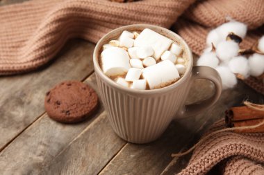 Tahta arka planda kurabiye ve süveter olan bir fincan kakao, yakın plan. Merhaba kış.