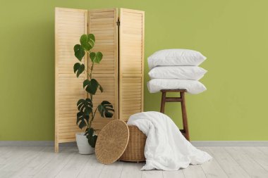 Interior of room with white bed sheets, basket and folding screen