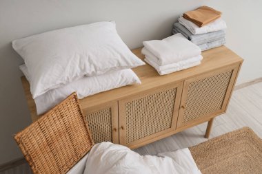 Oda odasındaki ışık duvarının yanındaki çekmecelerin üzerinde katlanmış yatak örtüleri.