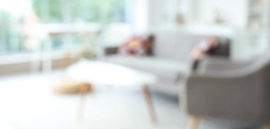 Gri kanepesi, koltuğu ve masaları olan bulanık oturma odası manzarası