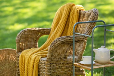 Konforlu hasır koltuk ve çaydanlık parkta, dışarıda servis arabasında.