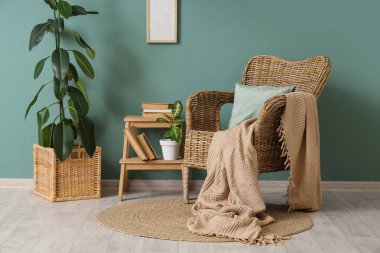 Hasır koltuklu, çiçekli ve mavi duvarlı kitaplarla dolu bir oda.