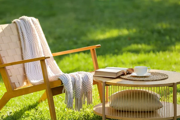 Rahat hasır koltuk, battaniye, kitap ve kahve ile parkta, açık havada.
