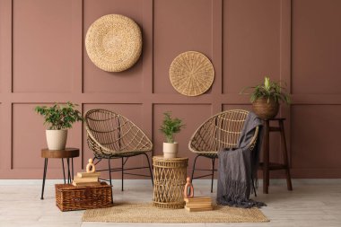 Hasır koltukları, masası ve bitkileri olan bir oda.