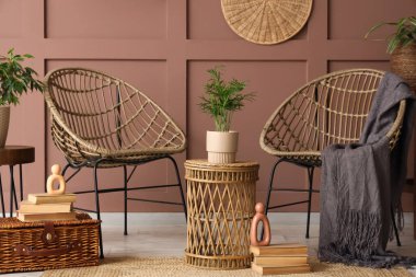 Hasır koltukları, masası ve bitkileri olan bir oda.