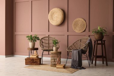 Hasır koltukları, masası ve bitkileri olan bir oda.