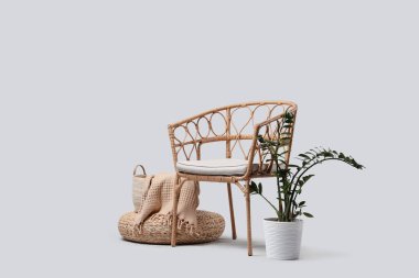 Açık arkaplanda puf ve bitki olan hasır koltuk