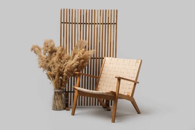 Çimenli vazo, tahta koltuk ve arka planda katlanır ekran.