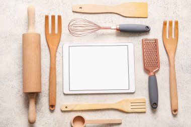 Beyaz grunge arka planında mutfak gereçleri olan dijital tarif kitabı