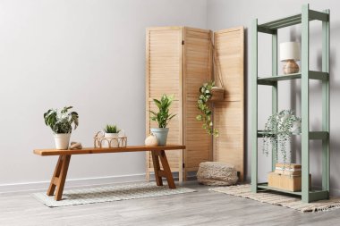 Odanın içinde ahşap bank, raf ünitesi ve bitkiler var.