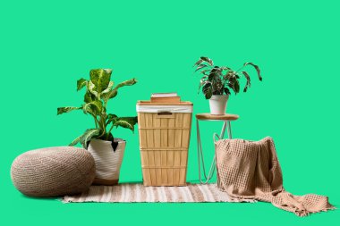 Masalı ahşap sepet, puf ve bitkiler yeşil arka planda