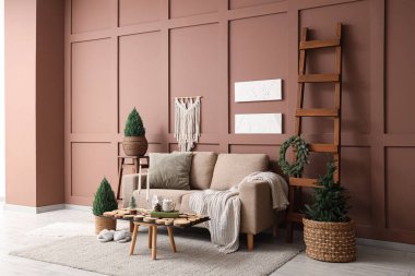 Oturma odasının içinde kanepe, Noel ağaçları ve yanan mumlar var.