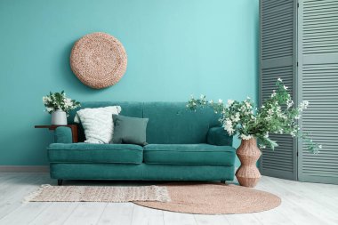 Oturma odasının içinde kanepe, katlanan perde ve çiçekli vazolar.