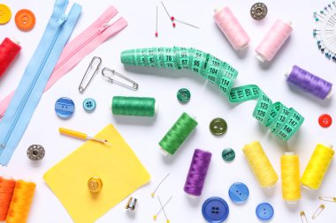 Set of thread spools with fabric, measuring tape and sewing supplies on white background