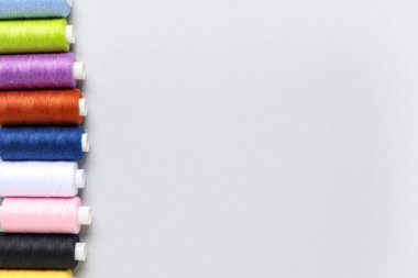 Row of colorful thread spools on grey background