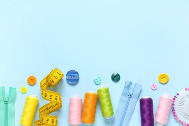 Set of thread spools with measuring tape and sewing supplies on blue background