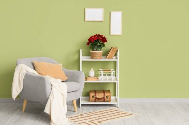 Interior of living room with Christmas plant poinsettia on shelf and armchair
