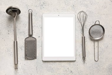 Beyaz grunge arka planında mutfak gereçleri olan dijital tarif kitabı