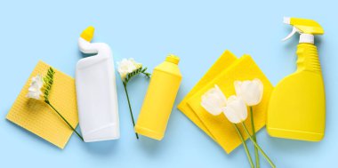 Aletlerle temizlik malzemeleri ve mavi arka planda güzel çiçekler.