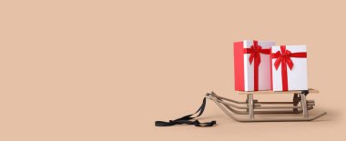 Bej arka planda Noel hediyeleriyle kızak ve metin için yer