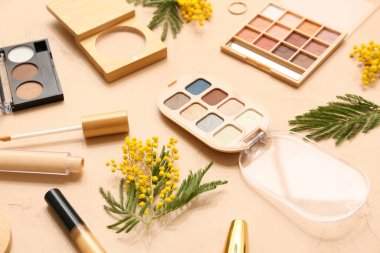 Bej arka planda dekoratif kozmetik ve mimoza çiçekleri, yakın plan