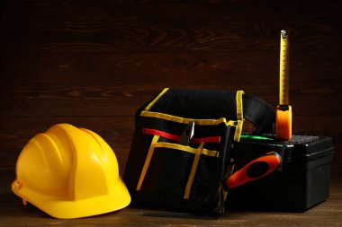 Ahşap arka planda inşaat araçları olan sert şapka ve kutu, yakın plan