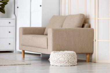 Oturma odasının iç tarafındaki gri kanepenin yanında örülmüş puf.