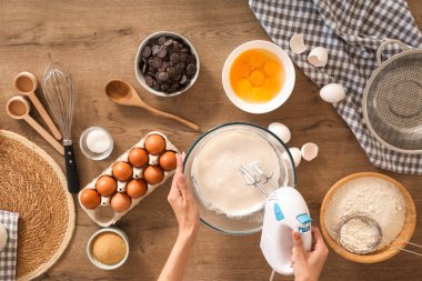 Mutfaktaki masanın üstünde mikser kullanan kadın elleri.