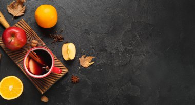 Siyah arka planda elma ve portakallı sıcak şarap.