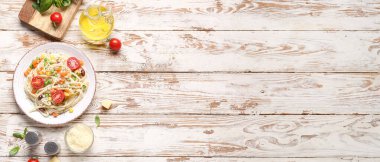 Lezzetli makarnalı primavera tabağı ve beyaz ahşap arka planda malzemeler.