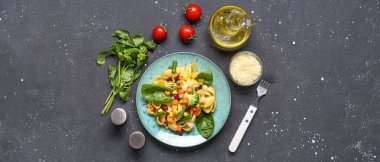 Lezzetli makarnalı primavera tabağı ve siyah arka plandaki malzemeler.