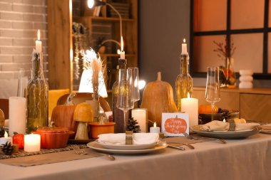 Akşamki Şükran Günü yemeği için yanan mumlar, balkabakları ve tebrik kartları olan güzel bir masa.