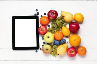 Tablet bilgisayar ve beyaz ahşap arka planda taze meyveler. Dünya Vegan Günü kavramı