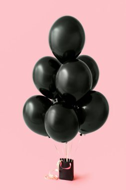 Pembe arka planda güzel hava balonları olan bir alışveriş çantası. Kara Cuma konsepti
