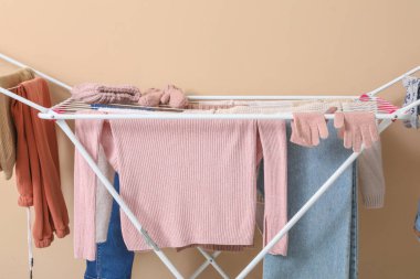 Bej arka planda kışlık giysileri olan kurutucu.