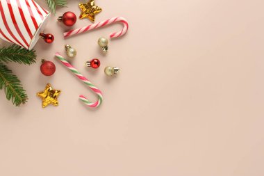 Fincanlı kompozisyon, baston şekerler, köknar ağacı dalları ve arka planda Noel topları