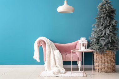 Oturma odasının içinde Noel ağacı, masa ve koltuk var.