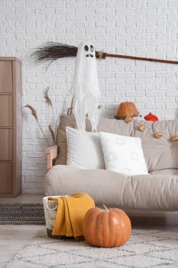 Cadılar Bayramı için dekore edilmiş oturma odasının içinde hayalet, cadı süpürgesi ve kanepe var.