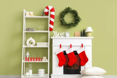 İçinde raf ünitesi ve şöminede Noel çorapları olan bir oda.