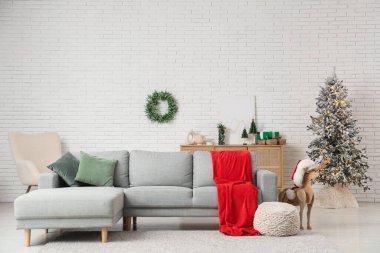 Kırmızı ekose, ahşap rengeyiği ve Noel 'de oturma odasının içinde ökseotu çelengi olan rahat bir kanepe.