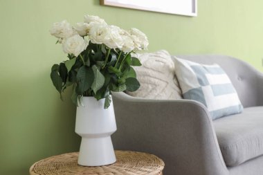 Oturma odasında sepetinde beyaz güller olan vazo.