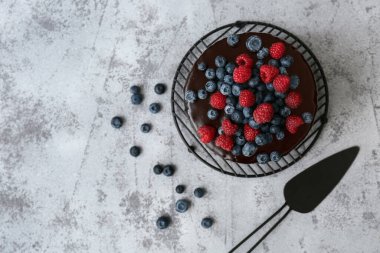 Gri arka planda taze böğürtlenli tatlı çikolatalı pasta.