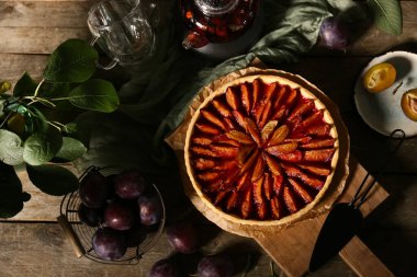 Lezzetli erikli turta, spatula, çaydanlık çay ve fincanlar ahşap masada.