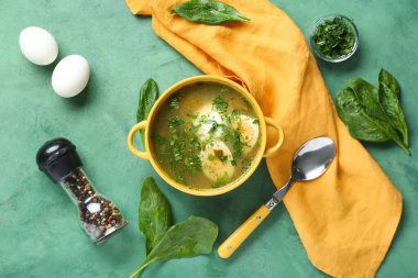 Yumurtalar, biberler, ıspanak yaprakları ve yeşil grunge arka planda kaşık ile lezzetli yeşil borş çorbası.