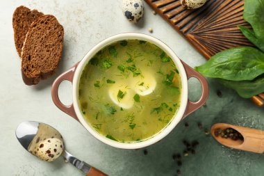 Yumurtalı, baget dilimli, biberli ve grunge arka planda ıspanak yapraklı lezzetli yeşil borş çorbası.