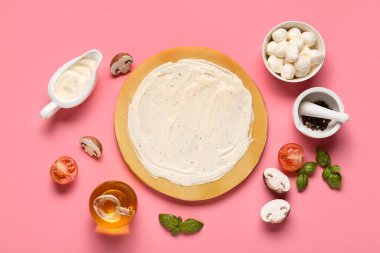 Lezzetli soslu pizza hamuru ve pembe arka planda malzemeler