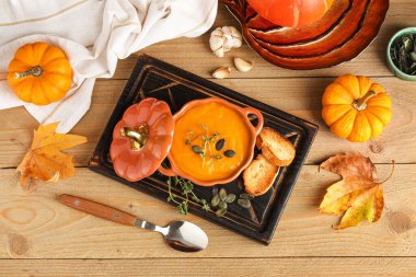 Tahta arka planda çekirdekli, kıtır kıtır ve kekik soslu lezzetli balkabağı kremalı çorba.