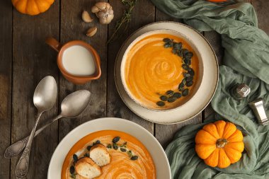 Tohumlu, kızarmış ekmek ve ahşap kaplama sarımsaklı balkabağı kremalı çorba kaseleri.